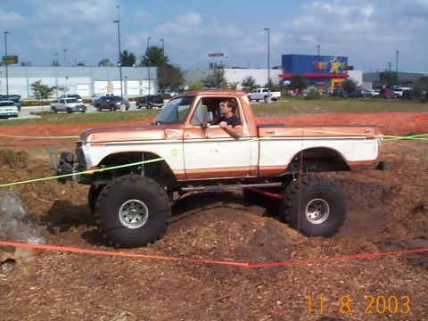 1992 Ford Bronco - A man drives a heavily modified pickup truck through an obstacle course with a Toys "R" Us in the background.