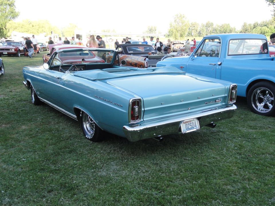 Light blue convertible car parked on grass, rear view. License plate reads 02504