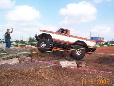 1992 Ford Bronco - A lifted pickup truck, likely from the late 1970s, tackles a challenging obstacle course made of logs and dirt.