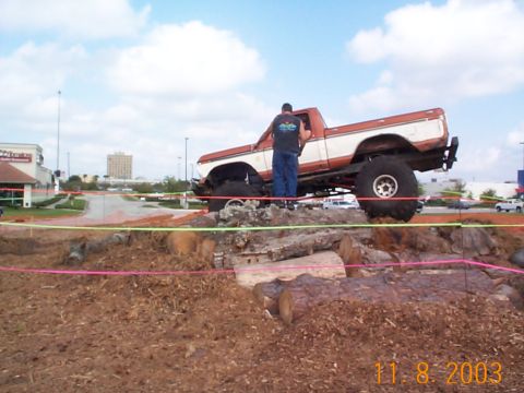 1992 Ford Bronco - Pickup truck navigating an off-road obstacle course made of logs and dirt.