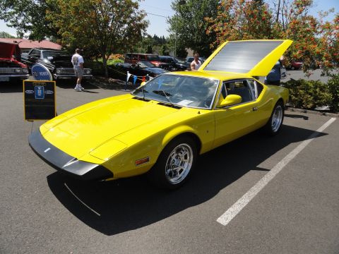 1964 Ford Fairlane - A bright yellow sports car is displayed with its rear hatch open at a car show.