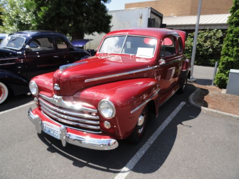 1964 Ford Fairlane - Red 1946 Ford coupe with chrome grille and trim, parked outdoors.