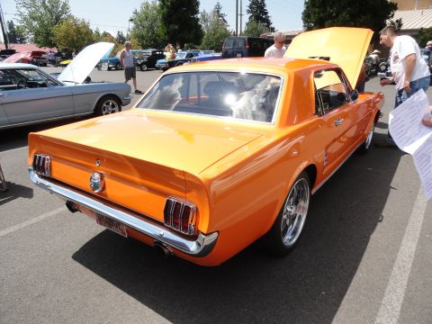 1964 Ford Fairlane - An orange coupe is parked next to a silver coupe at an outdoor car show.