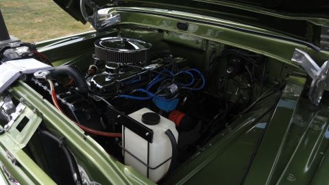 1964 Ford Fairlane - The engine bay of a green vehicle is shown with the hood open, revealing the motor and various components.