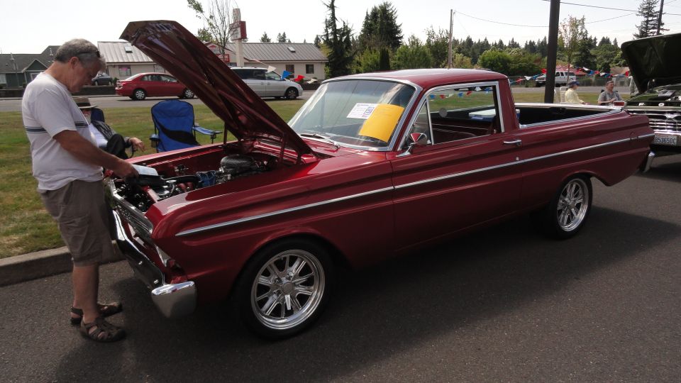 man looking at engine of red 1964 Ford Falcon Ranchero