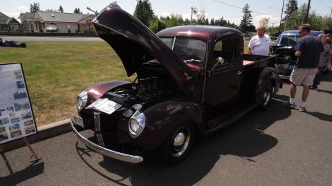 1964 Ford Fairlane - A maroon 1940 Ford pickup truck is displayed with its hood open, alongside other vehicles and people.