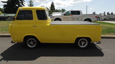 1964 Ford Fairlane - A yellow 1965 Ford Econoline pickup truck is parked next to a white Ford F-150 pickup truck.