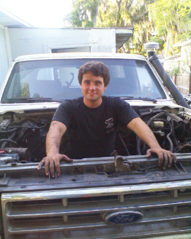 1988 Ford Bronco - Man poses in the engine bay of a Ford truck, likely an F-Series model from the late 1980s.