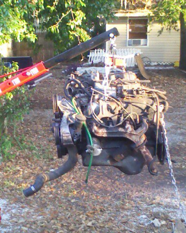 1988 Ford Bronco - An engine is suspended in the air by a crane, ready for removal or installation.