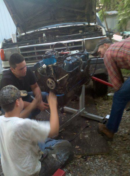 1988 Ford Bronco - People working on an engine that has been removed from a truck.