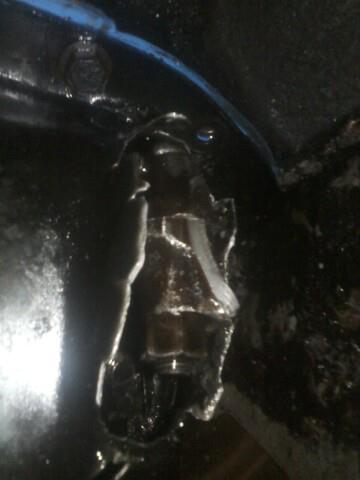 1988 Ford Bronco - A close-up view of a dark, oily engine part with some debris.