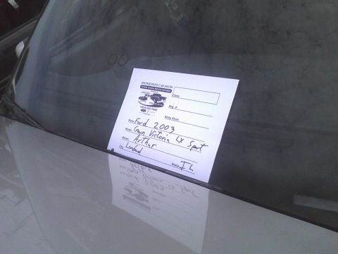 2003 Ford Crown Victoria - A sign on a car windshield details the vehicle's make, model, and owner information for a car show.