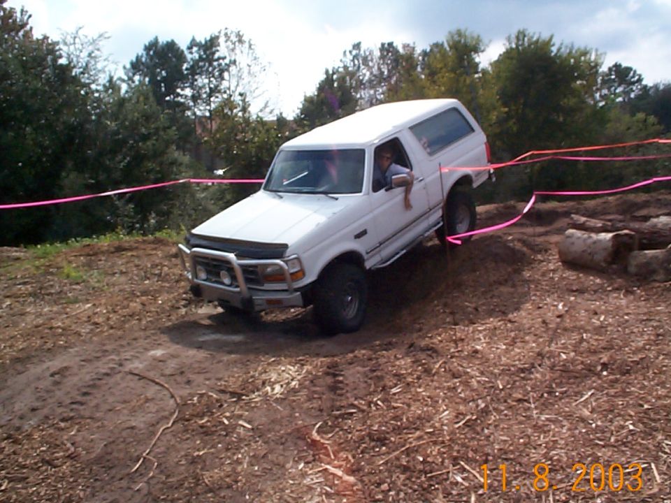 White Ford Bronco flexing a wheel off the ground on a taped dirt off-road course