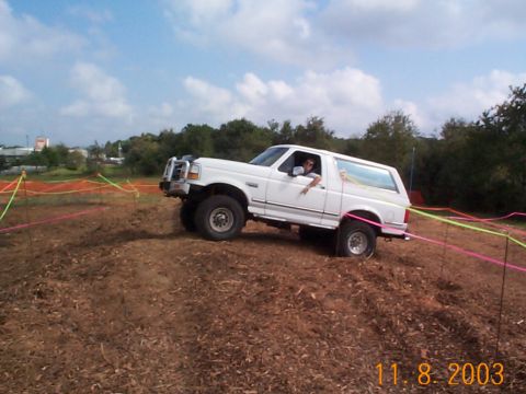 1992 Ford Bronco - White 1992 Ford Bronco navigates an off-road course marked with ribbons.