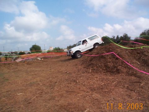 1992 Ford Bronco - A white SUV navigates an off-road course marked with colorful ribbons on a sunny day.
