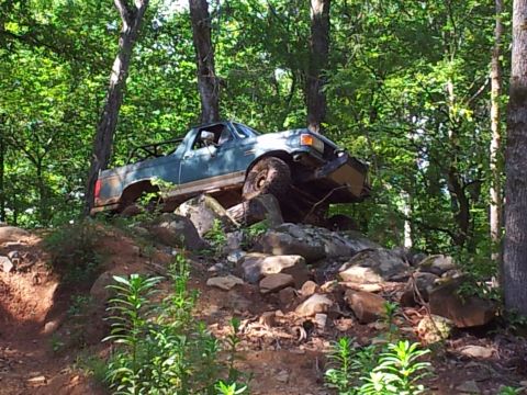 2012 Ford Bronco - Off-road truck navigating a challenging rocky trail through a wooded area.
