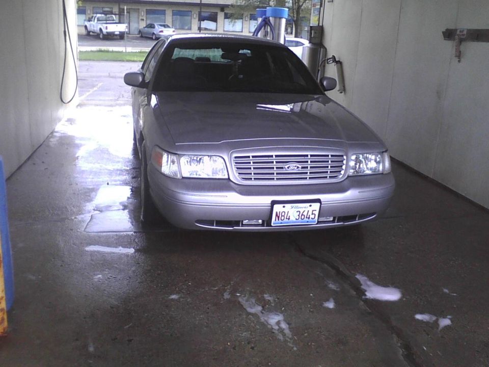 Silver 2003 Ford Crown Victoria with a chrome grille and license plate N84 3645, parked inside a car wash bay