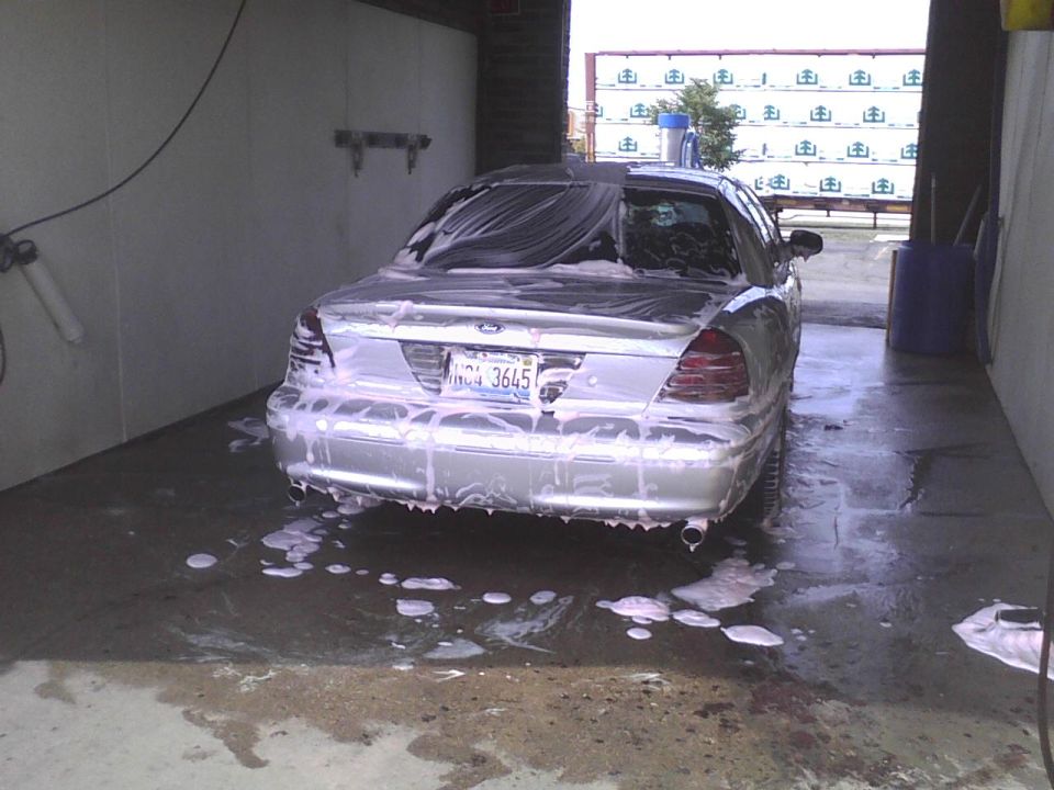 Rear view of a silver 2003 Ford Crown Victoria covered in soap at a car wash