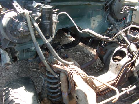 1995 Ford Bronco - Close-up view of the engine bay and suspension components of a vehicle, showing various mechanical parts and hoses.