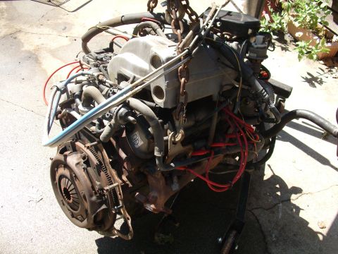 1995 Ford Bronco - This engine and transmission assembly is suspended by chains, showing its various components and connections.