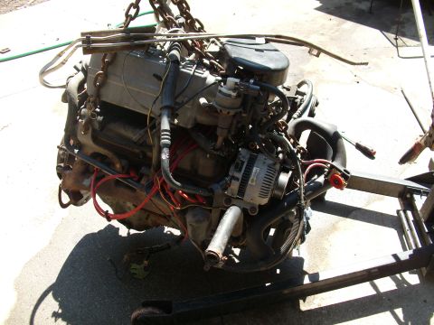 1995 Ford Bronco - Engine assembly, likely V8, suspended by chains for removal or installation.