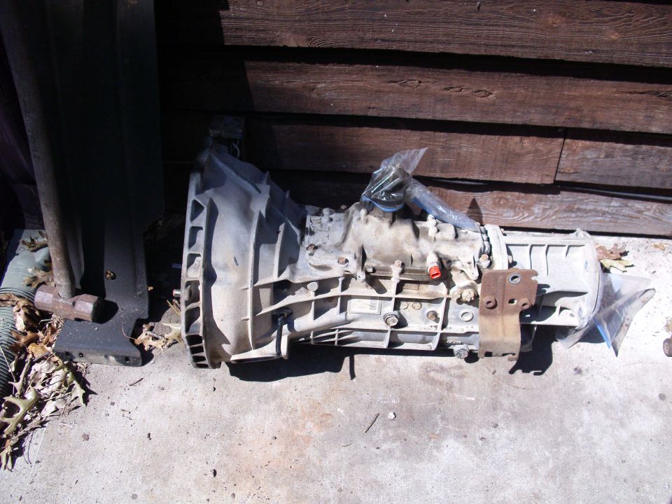 Transmission assembly resting on concrete in front of a wooden wall