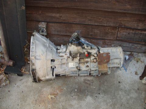 1995 Ford Bronco - A transmission part is shown resting on a concrete surface next to a wooden wall.