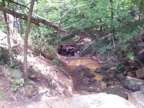 2012 Ford Bronco - Off-road vehicle navigating a challenging muddy obstacle course in a wooded area.