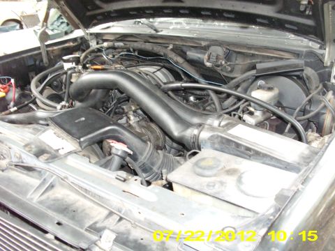 1988 Ford Bronco - The engine bay of a vehicle is shown with the hood open, revealing the engine components and associated wiring and hoses.