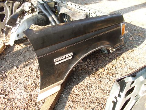 1988 Ford Bronco - A detached black fender with 'Bronco' badging is shown, alongside other vehicle components.