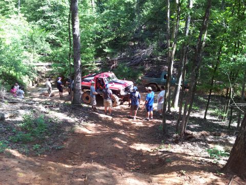 2012 Ford Bronco - Several people gather around off-road vehicles on a dirt trail in a wooded area.