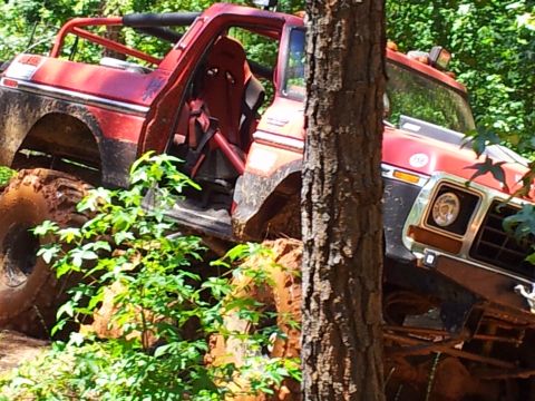 2012 Ford Bronco - This red SUV is navigating a challenging off-road course, with its tires deep in mud.