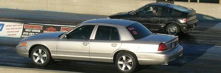 2003 Ford Crown Victoria - A silver 2003 Ford Crown Victoria competes in a drag race alongside another vehicle.