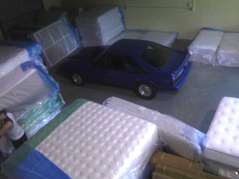 2003 Ford Crown Victoria - A blue coupe is parked in a warehouse surrounded by mattresses.