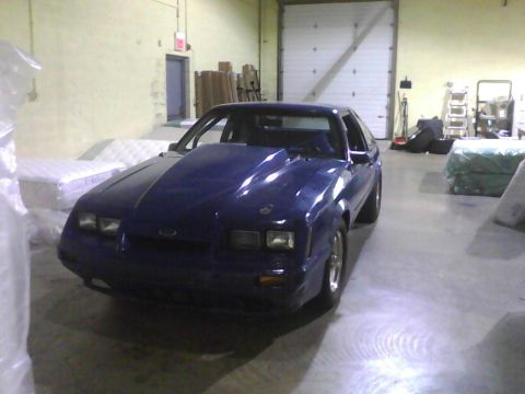 2003 Ford Crown Victoria - This blue coupe features a prominent hood scoop and is parked indoors.