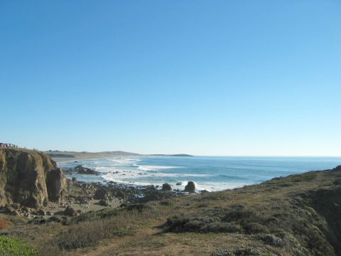 2002 Ford Taurus - Ocean view from a cliffside, with waves and rocks. Cars are visible on the cliff in the distance.
