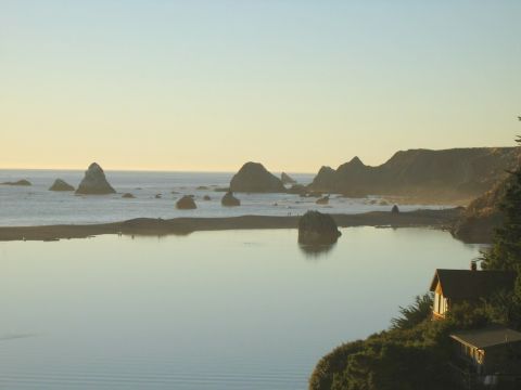 2002 Ford Taurus - A coastal scene at sunset features sea stacks and a small dwelling overlooking the water.