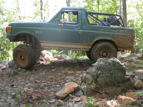1990 Ford Bronco - 1990 Ford Bronco navigating a rocky trail with its suspension flexed.