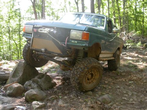 1990 Ford Bronco - This modified 1990 Ford Bronco navigates a rocky trail with its front tire elevated.