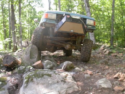 1990 Ford Bronco - Modified 1990 Ford Bronco tackling a challenging off-road course with large rocks.