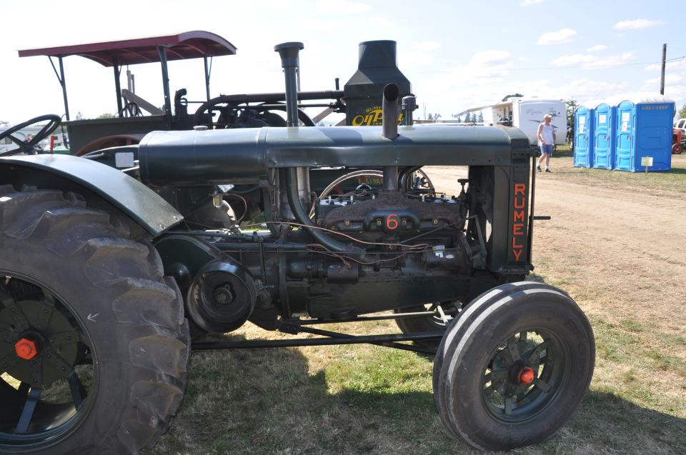 Dark green Rumely tractor with exposed engine and large rear wheels