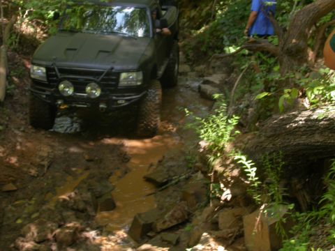 1990 Ford Bronco - This black 1992 Ford F-150 navigates a challenging off-road course with muddy terrain and rocks.