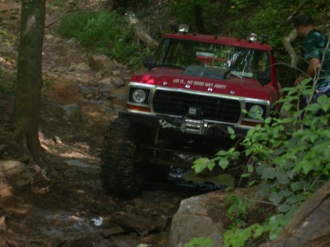1990 Ford Bronco - This red 1979 Ford Bronco is shown navigating a challenging off-road course with large tires and a lifted suspension.
