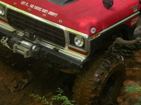 1990 Ford Bronco - This modified Ford Bronco is tackling a muddy off-road trail, a winch and custom hood decal.