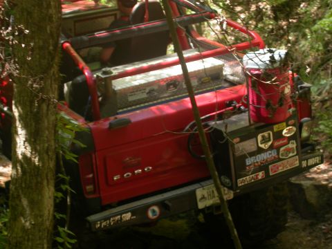 1990 Ford Bronco - 1990 Ford Bronco navigating a trail with off-road accessories visible.