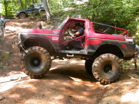 1990 Ford Bronco - This modified 1990 Ford Bronco navigates a challenging off-road course with its distinctive roll cage and oversized tires.