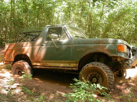 1990 Ford Bronco - This mud-covered Ford Bronco is navigating a challenging off-road trail.