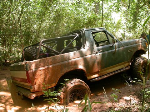 1990 Ford Bronco - This 1990 Ford Bronco is deep in the mud and water, with a roll cage installed.