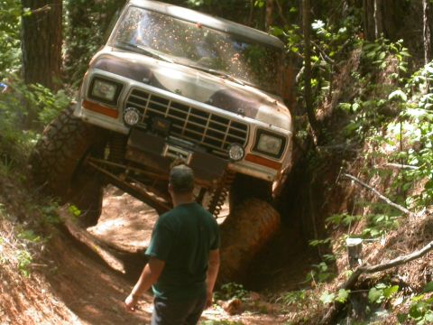 1990 Ford Bronco - Ford Bronco tackling a challenging off-road course in a wooded area.