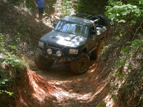 1990 Ford Bronco - Modified 1990 Ford Bronco tackles a challenging off-road course on a dirt trail.